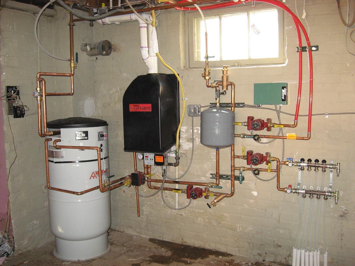 A basement with a tall indirect water heater, a wall-hung boiler and copper piping