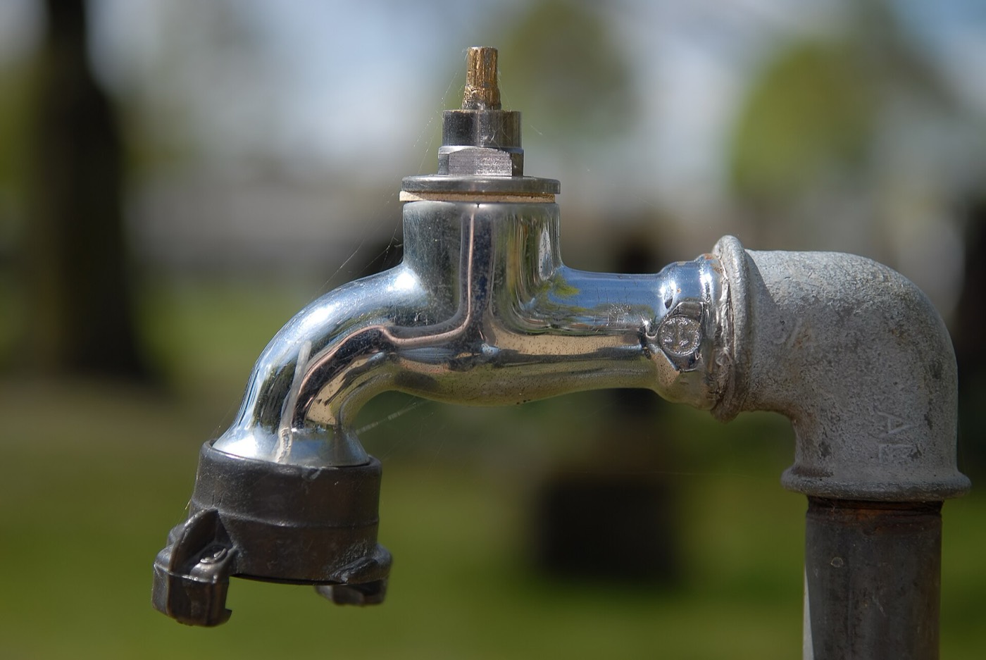 An old outdoor faucet on a galvanised supply pipe