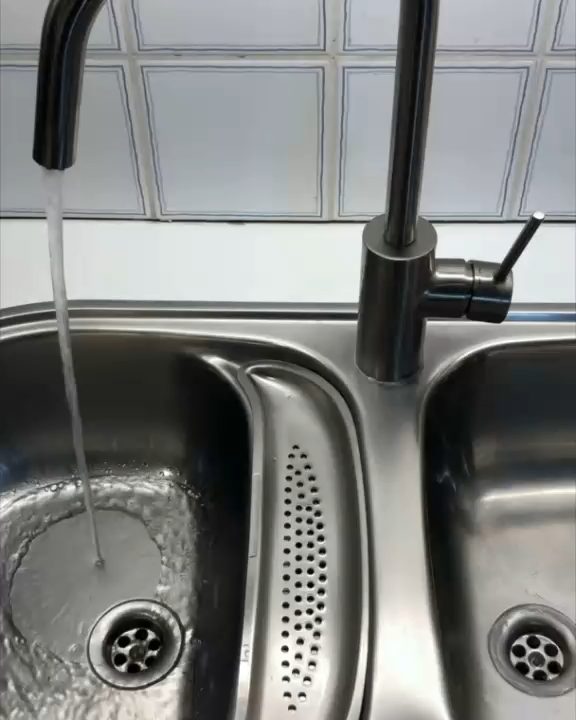 A steel kitchen faucet running into a double sink